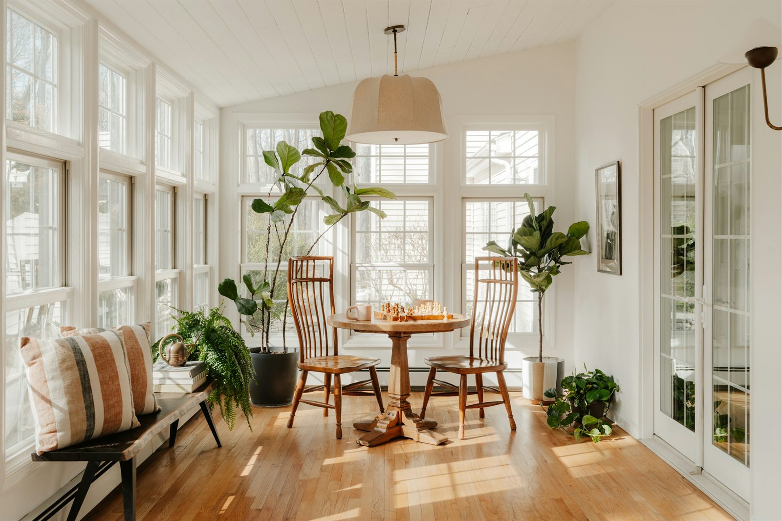 Véranda lumineuse et chaleureuse avec parquet, plantes et coin convivial, espace propice aux ateliers de sophrologie en petit groupe animés par Anaïs Leneau